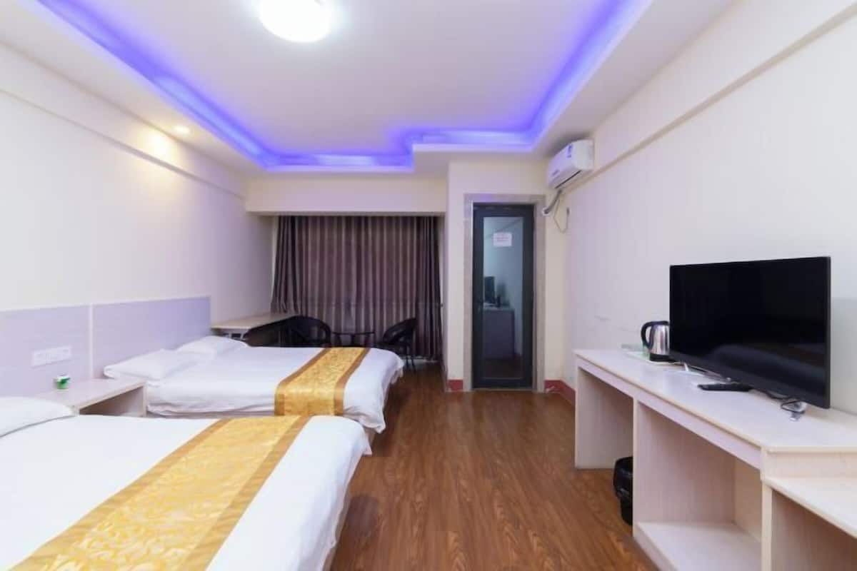 A hotel room with two beds, a TV, a desk, and a door leading to a bathroom.