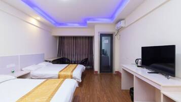 A hotel room with two beds, a desk, a chair, a television, and a minibar.