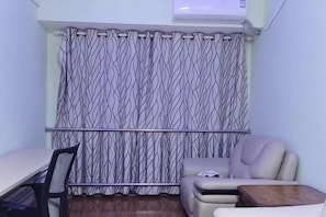 A room with a patterned curtain, a sofa, a small table, and a chair. - Lakefront Hotel (Shanghai)