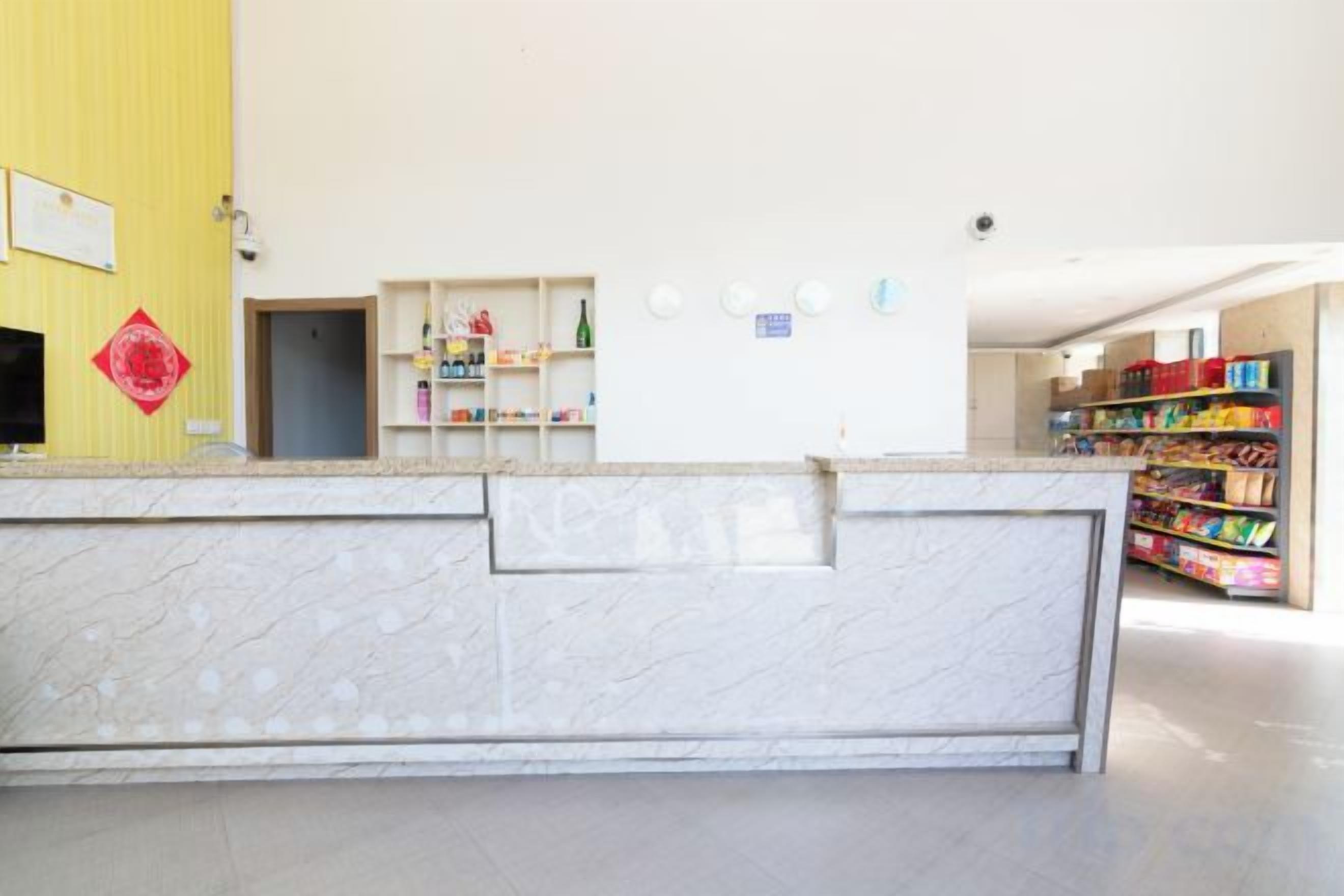 Een receptie met een marmeren balie, een gele wand en een boekenplank met diverse objecten.