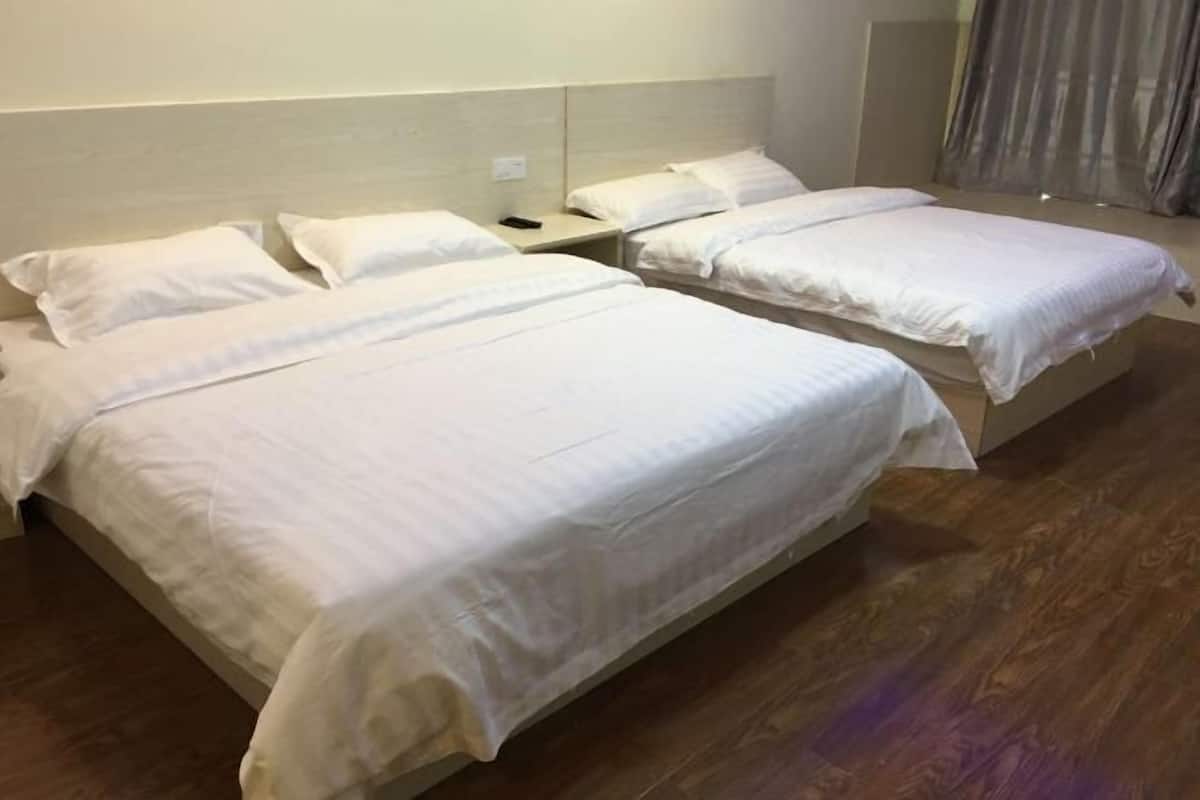 A hotel room with two beds, a nightstand, and a wooden floor.