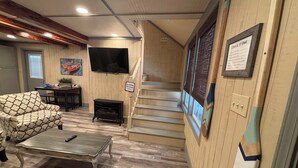 Una sala de estar con un sofá, una mesa de centro, un televisor y una escalera.