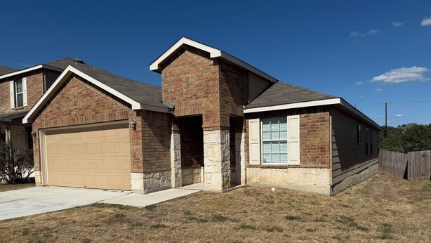 A two-story house with a garage, a stone foundation, and a brick exterior.