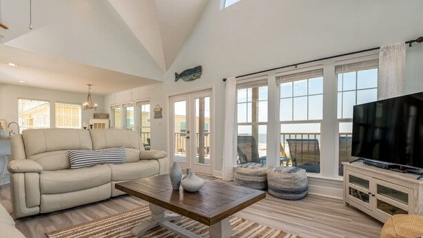 A spacious living room with a sofa, coffee table, and television. - Waterfront ~ Ohana  ~ Sleeps 10 (Dauphin Island)