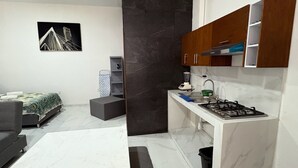 Une cuisine moderne dotée d’une cuisinière intégrée, de plans de travail en marbre blanc et de meubles de rangement aux couleurs sombres.