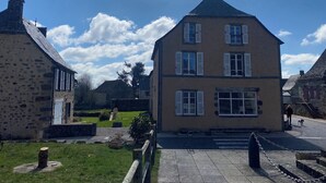 A two-story building with a steep gabled roof and white shutters. - "L'Hôtel d'O', a former coaching inn in a typical Cantal village. (Neuvéglise-sur-Truyère)
