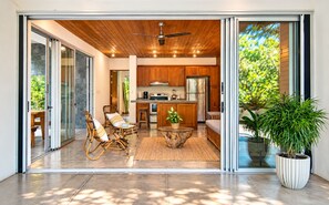 A modern kitchen with wooden cabinets, a stainless steel refrigerator, and a dining area with wicker chairs.
