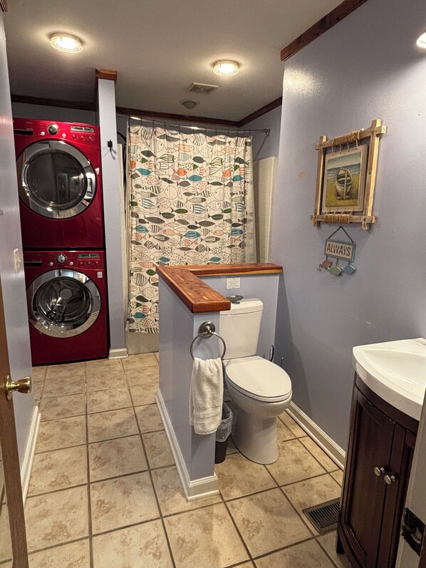 A compact bathroom with a toilet, sink, and a red washing machine. - The Cedar Cabin at Center Hill Lake (Smithville)