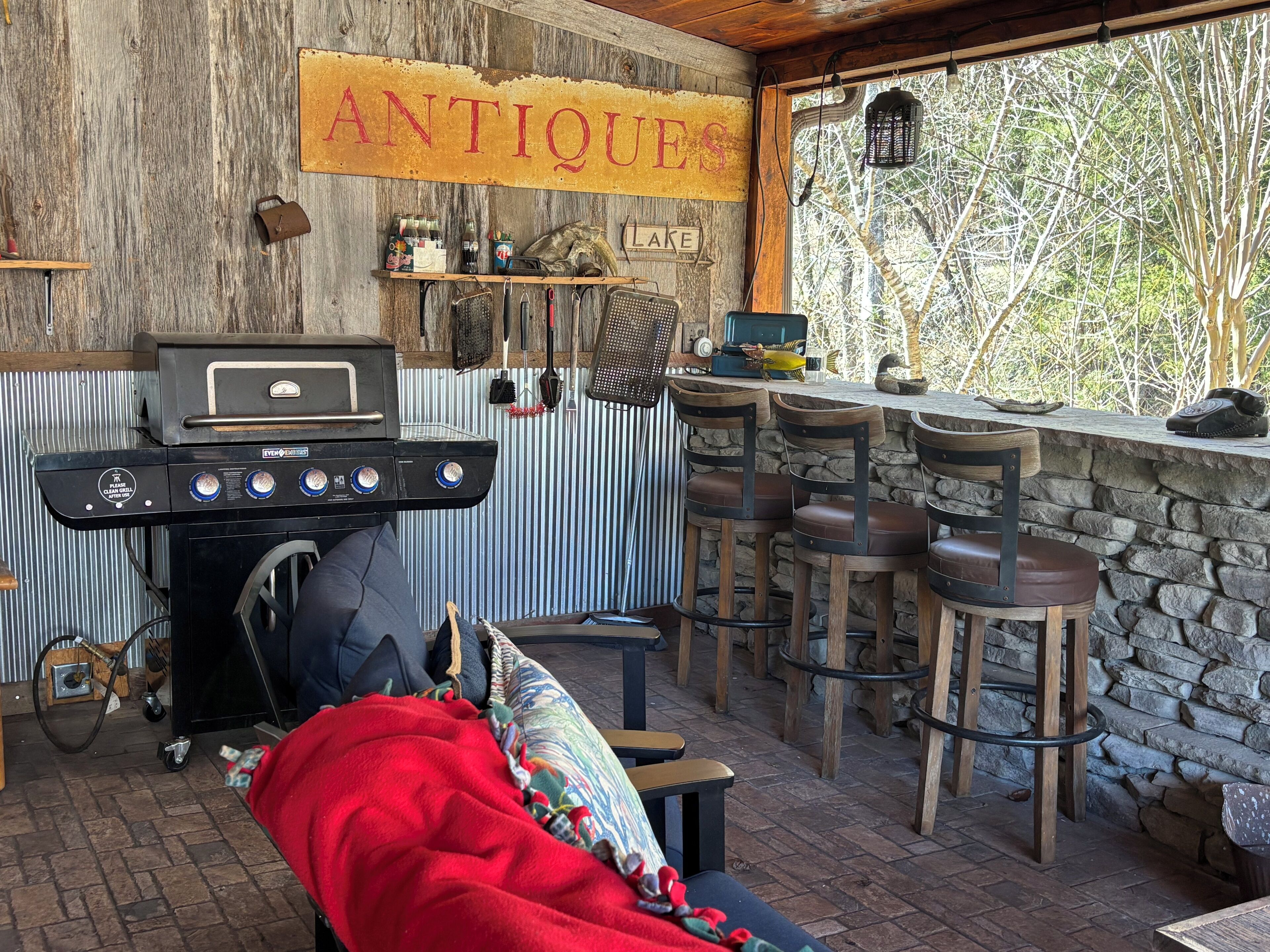 Un espace bar extérieur avec un barbecue, des tabourets de bar et une enseigne indiquant « ANTIQUE LAKE ».