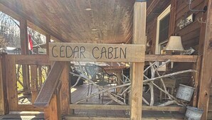 Una cabaña de madera con un cartel que dice "CEDAR CABIN" y un muro de piedra.