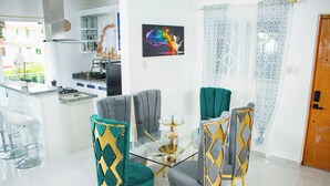 A modern kitchen with a dining area featuring a glass table and four chairs with geometric patterns.