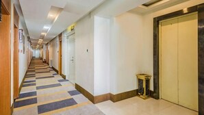 Ein Hotelkorridor mit Schachbrettmuster-Teppich, Türen und einem kleinen Tisch.