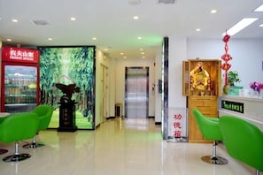 A hotel reception area with a digital display, green chairs, a statue, and a vending machine. - Shell Hotel (Chaoyang shoe city store, Chaoyang Street, Taiyuan) (Taiyuan)