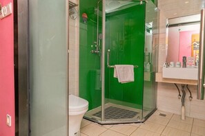 Ein Badezimmer mit Duschkabine, Toilette und Waschbecken mit Spiegel.