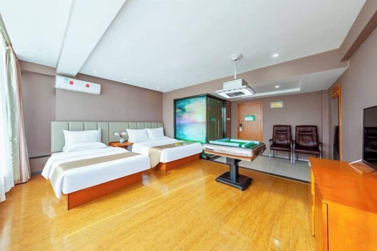Ett hotellrum med två sängar, ett skrivbord, en tv och ett biljardbord.