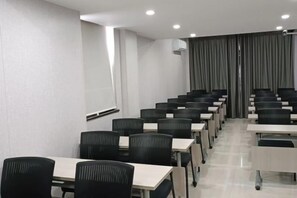 A conference room with rows of tables and chairs, a whiteboard, and an air conditioning unit. - Shell Hotel (Chaoyang shoe city store, Chaoyang Street, Taiyuan) (Taiyuan)
