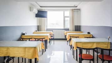 A classroom with tables and chairs, a window with curtains, and a radiator.