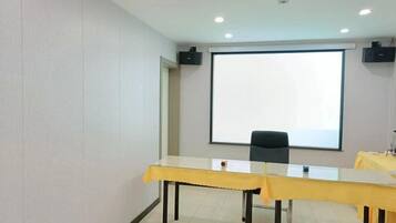 Una sala de conferències amb una gran pantalla de projecció, una taula amb estovell groc i una cadira negra.