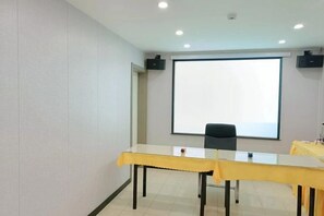 A conference room with a large projection screen, a table with a yellow tablecloth, and a black chair. - Shell Hotel (Chaoyang shoe city store, Chaoyang Street, Taiyuan) (Taiyuan)