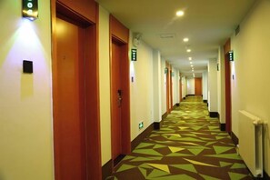 A hotel hallway with doors on both sides, a patterned floor, and emergency exit signs. - Shell Hotel (Chaoyang shoe city store, Chaoyang Street, Taiyuan) (Taiyuan)