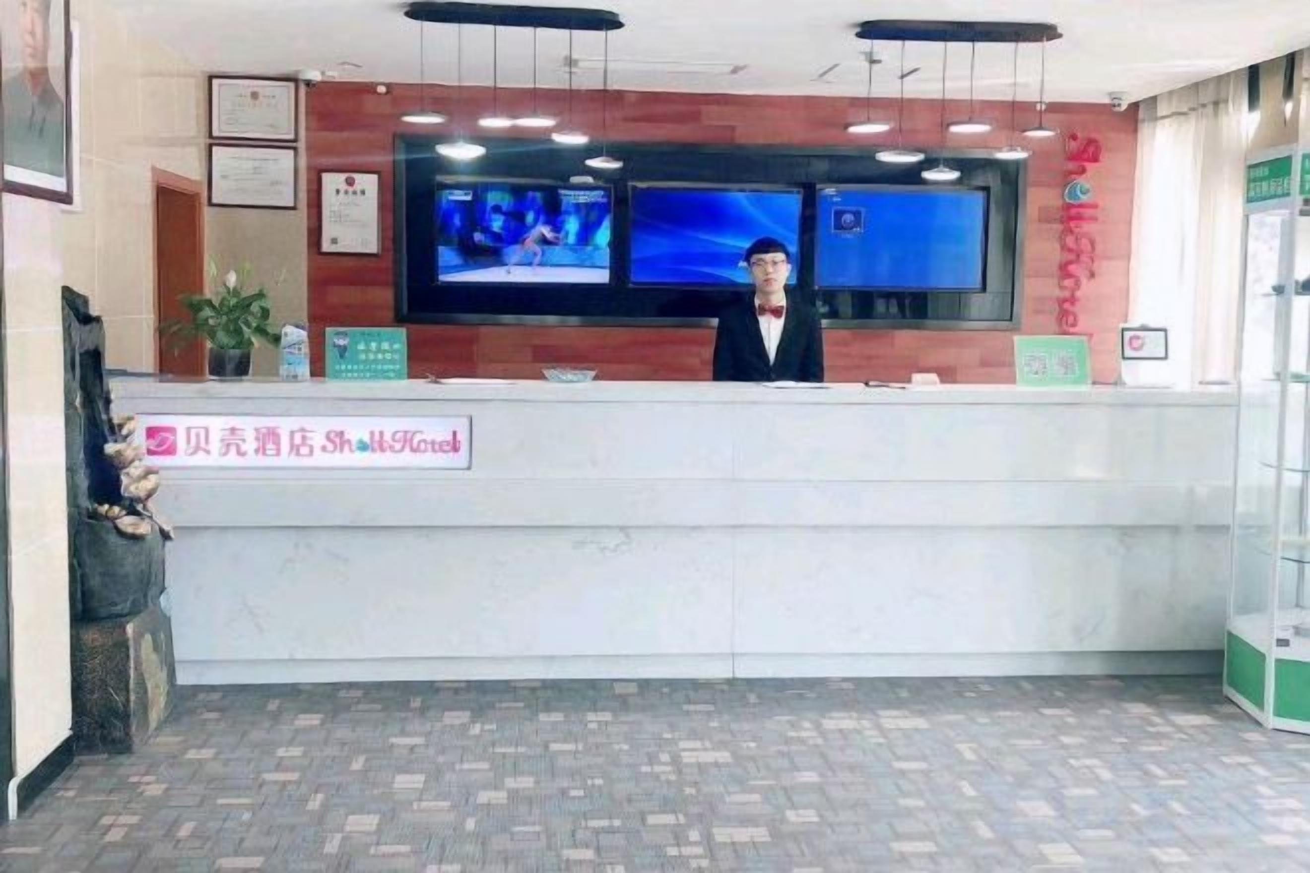 Una recepción de hotel con un televisor de pantalla plana, un reloj digital y un letrero con el nombre del hotel.