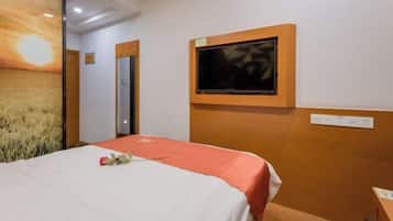 Een hotelkamer met een bed, een aan de muur bevestigde televisie en een deur naar een andere kamer.