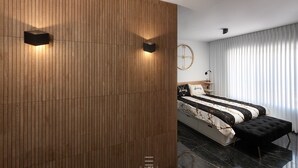 Un dormitorio moderno con un panel de madera en la pared, una cama con colcha a rayas negras y blancas y un reposapiés negro.