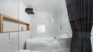 Un baño moderno con una bañera independiente, un inodoro y una zona de ducha con mampara de cristal.