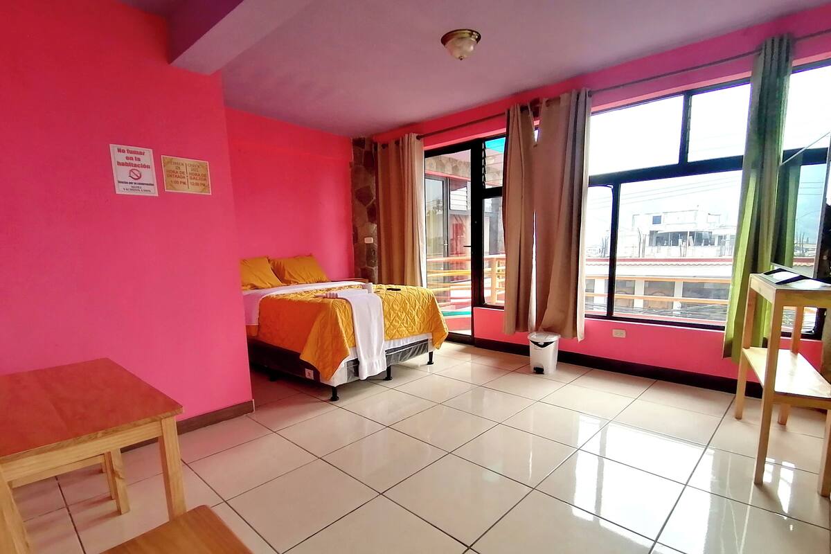 Ein Hotelzimmer mit Bett, Schreibtisch und einem Fenster mit Vorhängen.