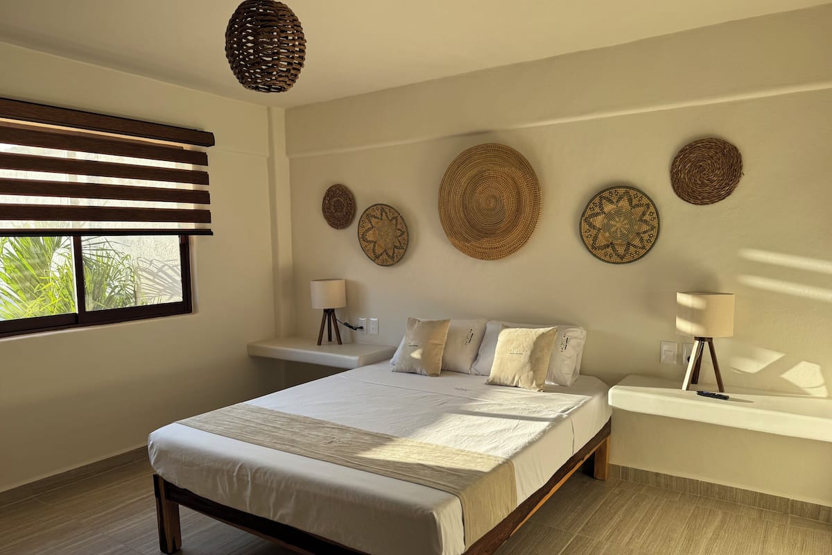 A bedroom with a bed, bedside tables, and wall decor.