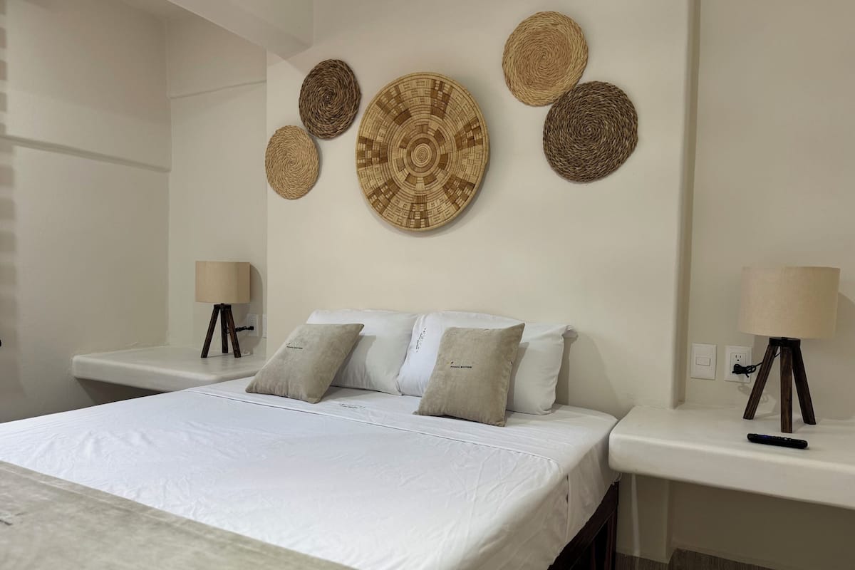 A bedroom with a bed, two bedside tables, a lamp on each table, and four wall-mounted woven baskets.