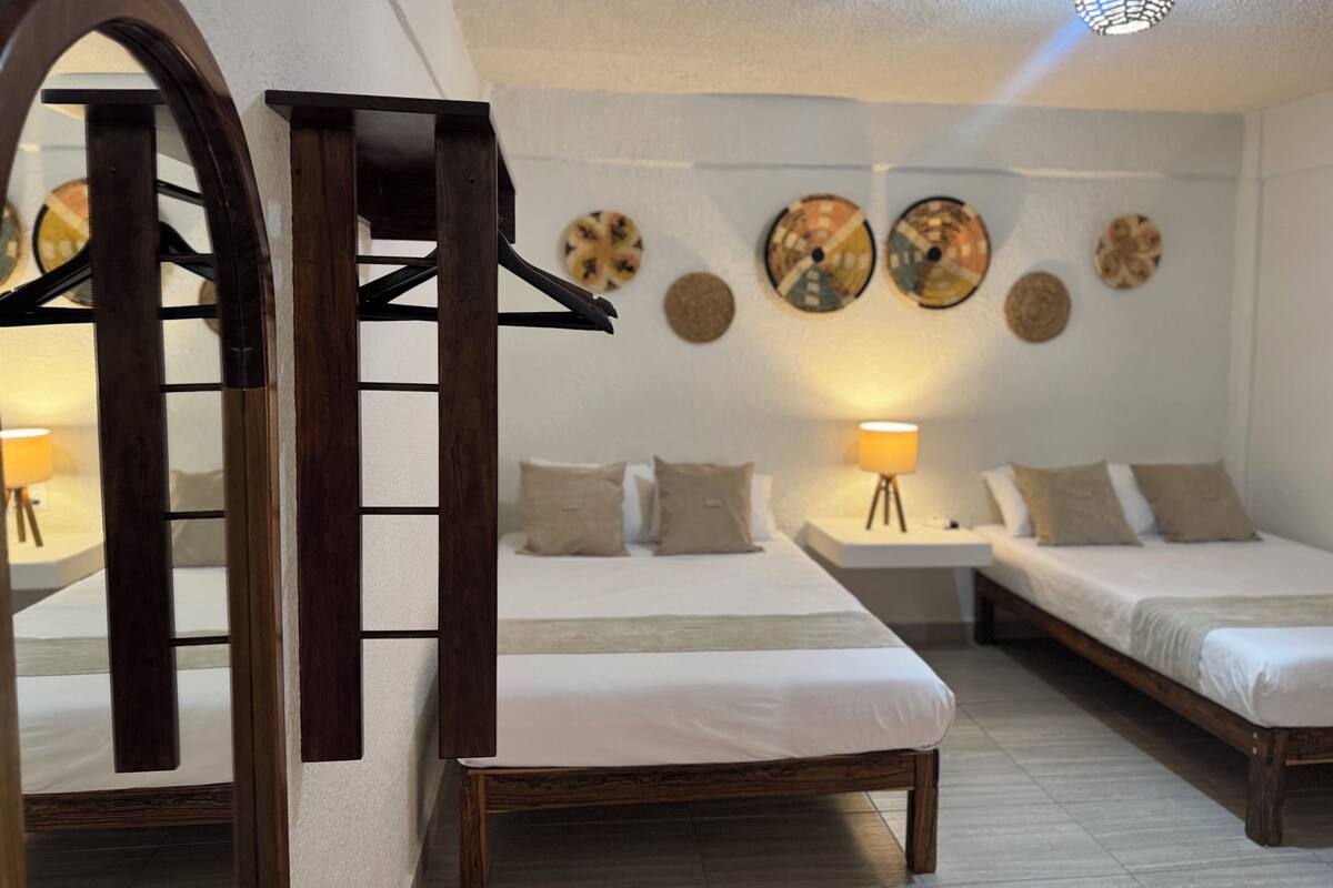 A hotel room with two beds, a wooden arched doorway, and wall decor.