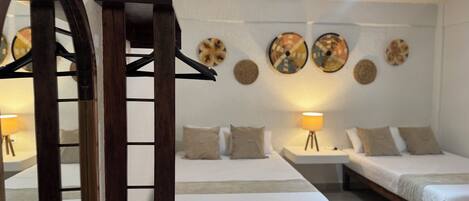 Habitación de hotel con dos camas, un arco de madera en la entrada y decoración en las paredes.
