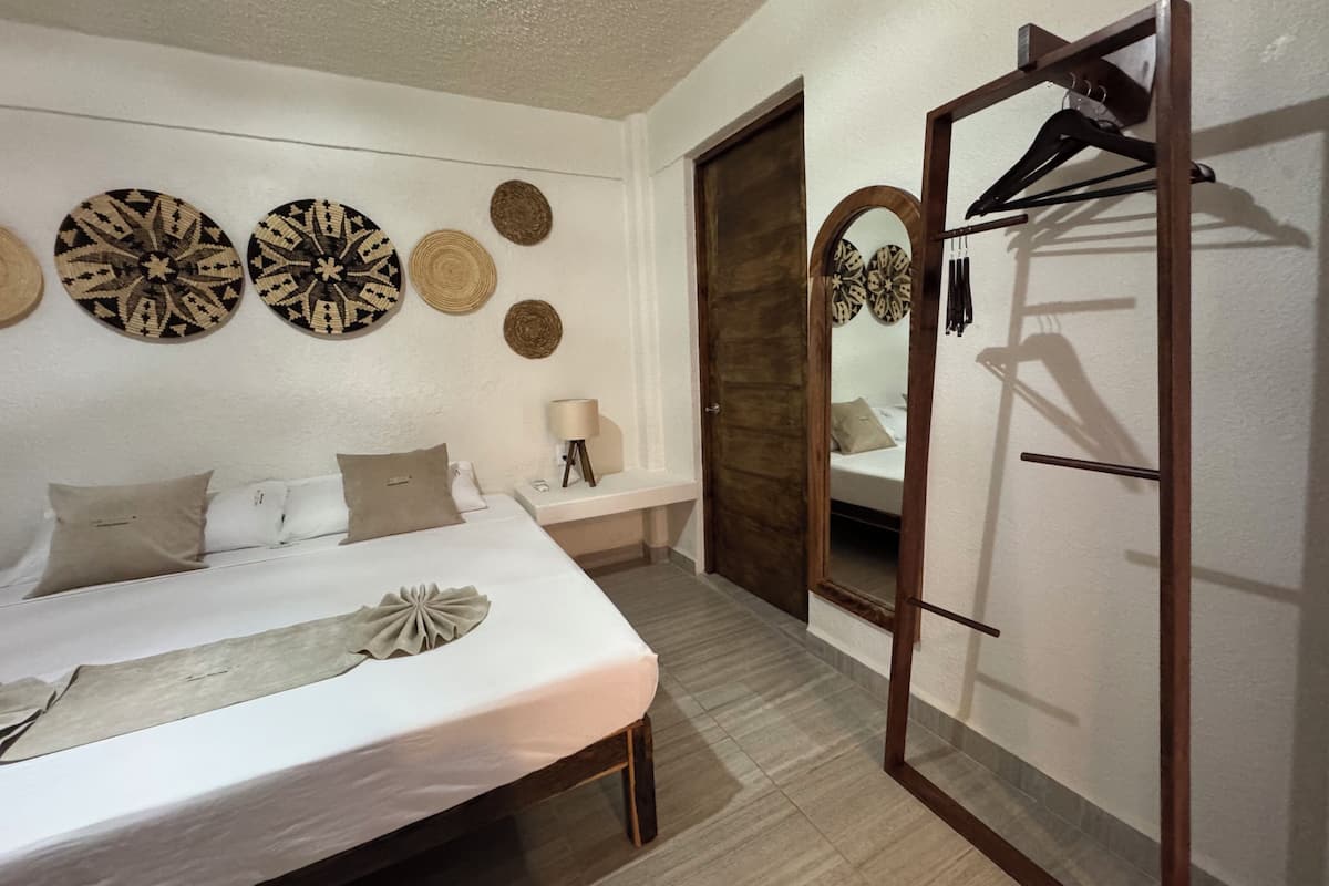 A hotel room with a bed, a mirror, a wardrobe, and wall decorations.