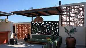 An outdoor seating area with a green sofa, a large potted plant, and a speaker system.