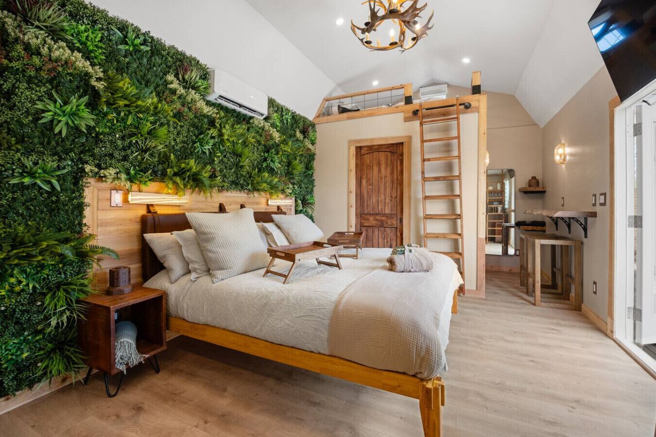 Une chambre avec un lit, une échelle en bois, un bureau et un mur vert.