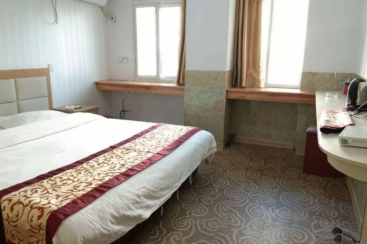 Ein Hotelzimmer mit Bett, Schreibtisch, Fenster und Bad.