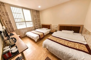 Habitación de hotel con dos camas, un escritorio y una ventana con cortinas.