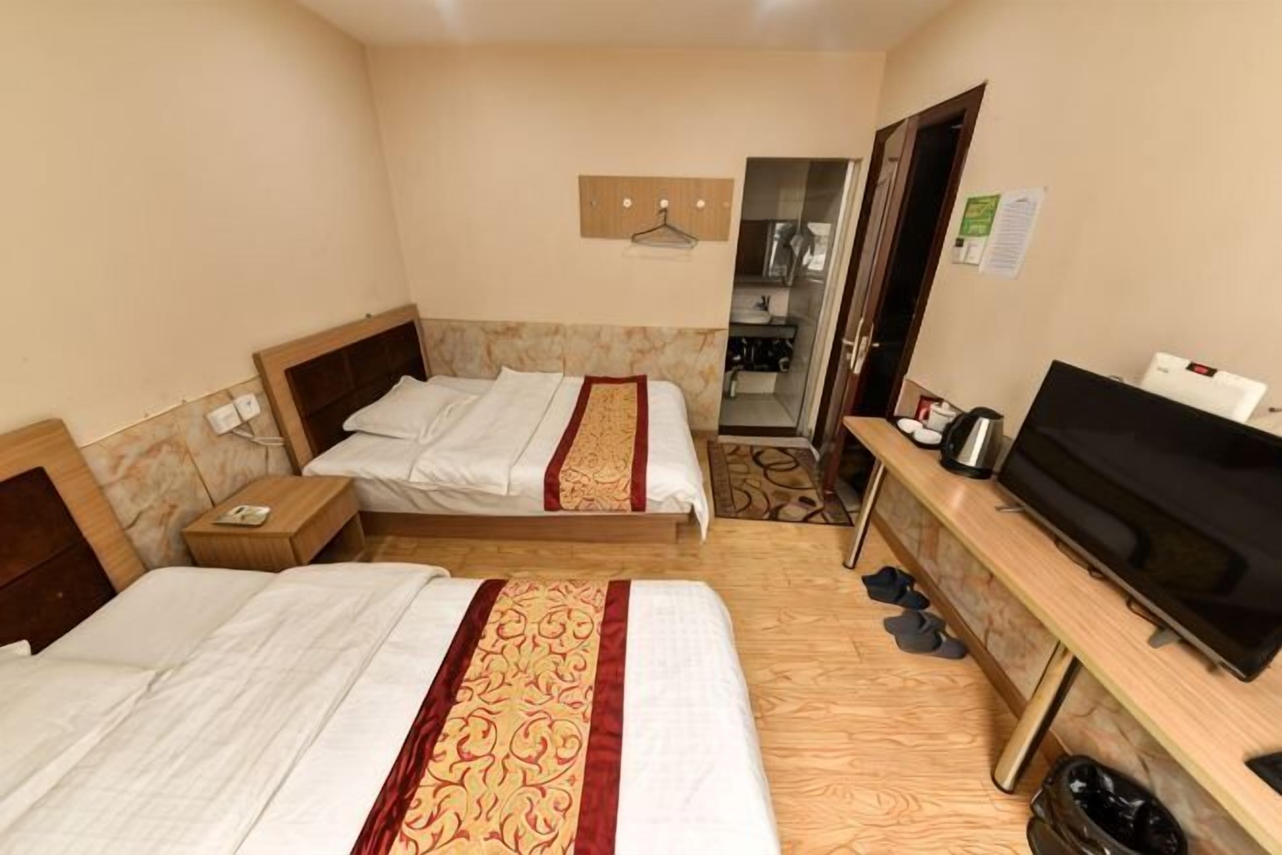 Habitación de hotel con dos camas, televisión, escritorio y espejo.