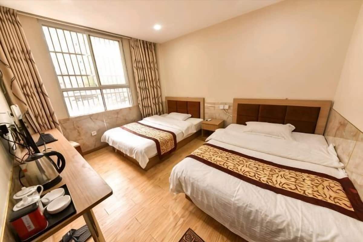 Une chambre d’hôtel avec deux lits, un bureau avec une chaise, une table avec une chaise et une fenêtre avec des rideaux.