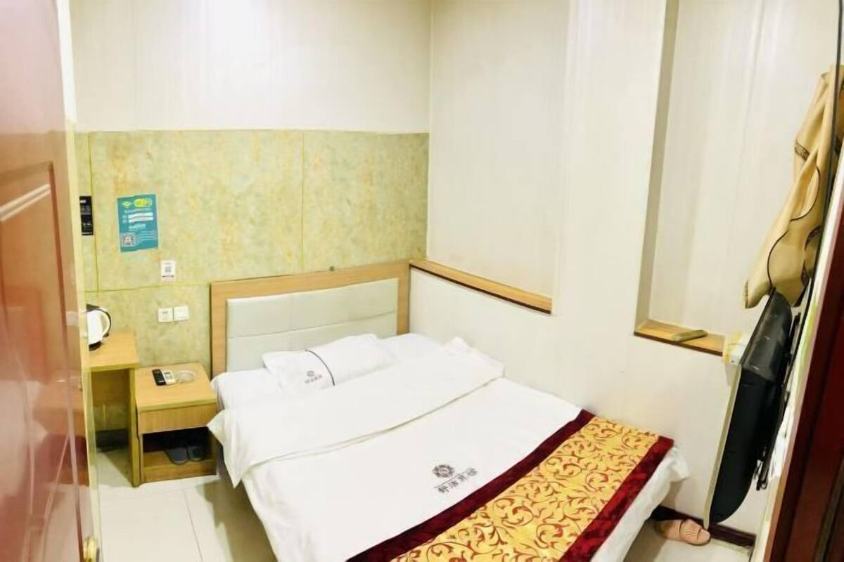 Une chambre d’hôtel équipée d’un lit, d’une table de chevet, d’un téléphone et d’un téléviseur.