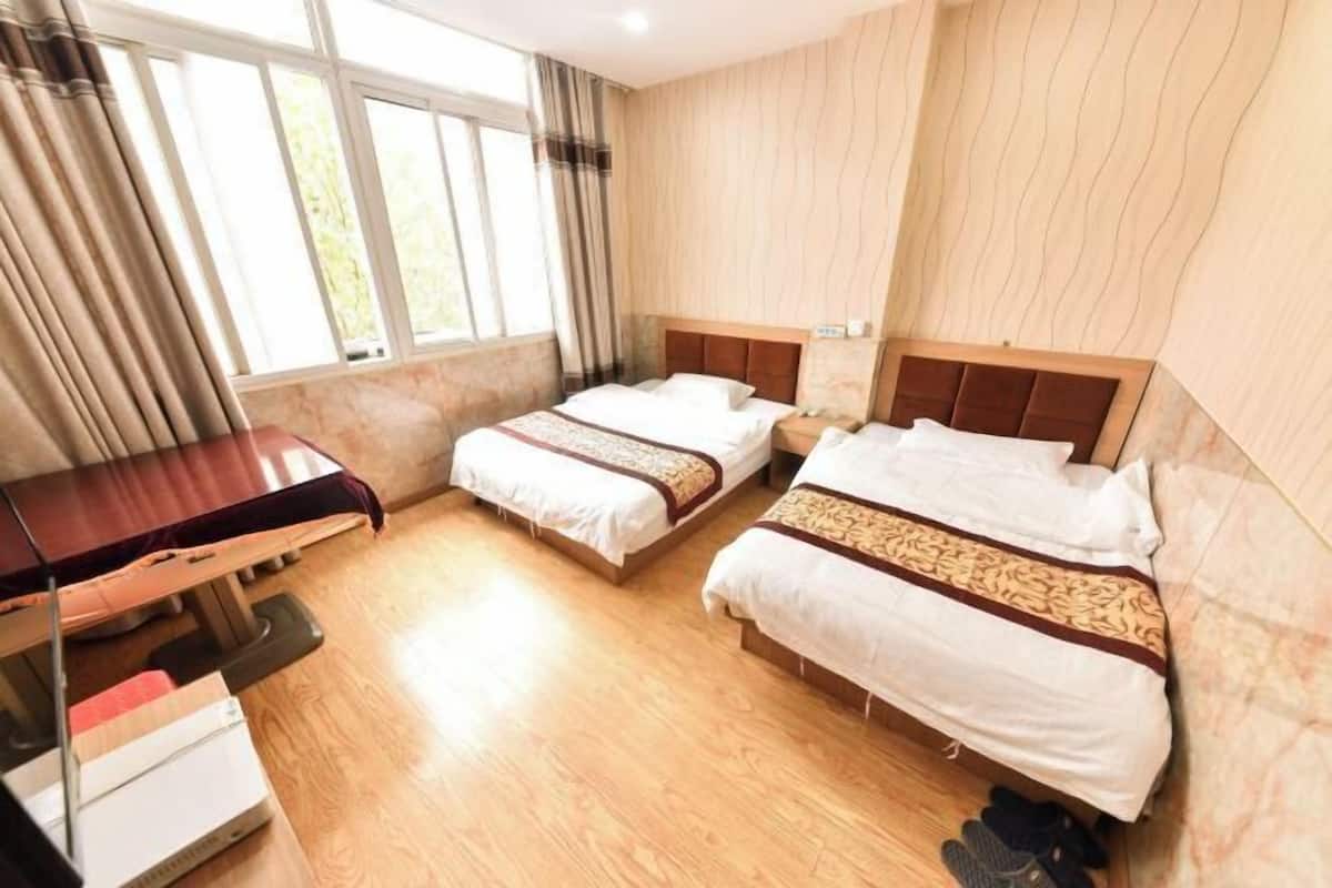 Une chambre d’hôtel avec deux lits, un bureau et une fenêtre avec des rideaux.