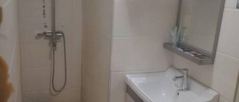 Ein Badezimmer mit Dusche, Waschbecken und Spiegel.