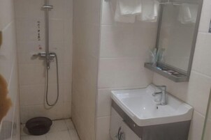 Un baño con ducha, lavabo y espejo.
