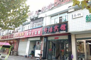 Una hilera de locales comerciales con persianas cerradas, uno con un letrero que anuncia el negocio 'Sheng Qiu An'.