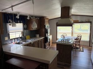 A kitchen with a central island, wooden cabinets, a built-in oven, and a window with blinds.