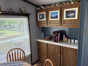 A kitchen with wooden cabinets, a coffee maker, and framed pictures on the wall.