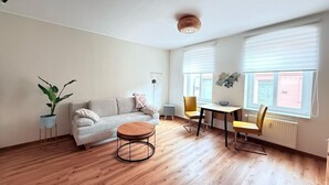 Una sala de estar moderna con un sofá, una mesa redonda de centro y un comedor con sillas.