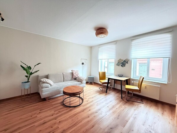 Ein modernes Wohnzimmer mit einer Couch, einem runden Couchtisch und einem Essbereich mit Stühlen.