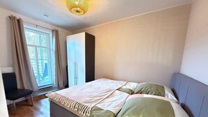 Un dormitorio con cama, armario, silla y ventana.